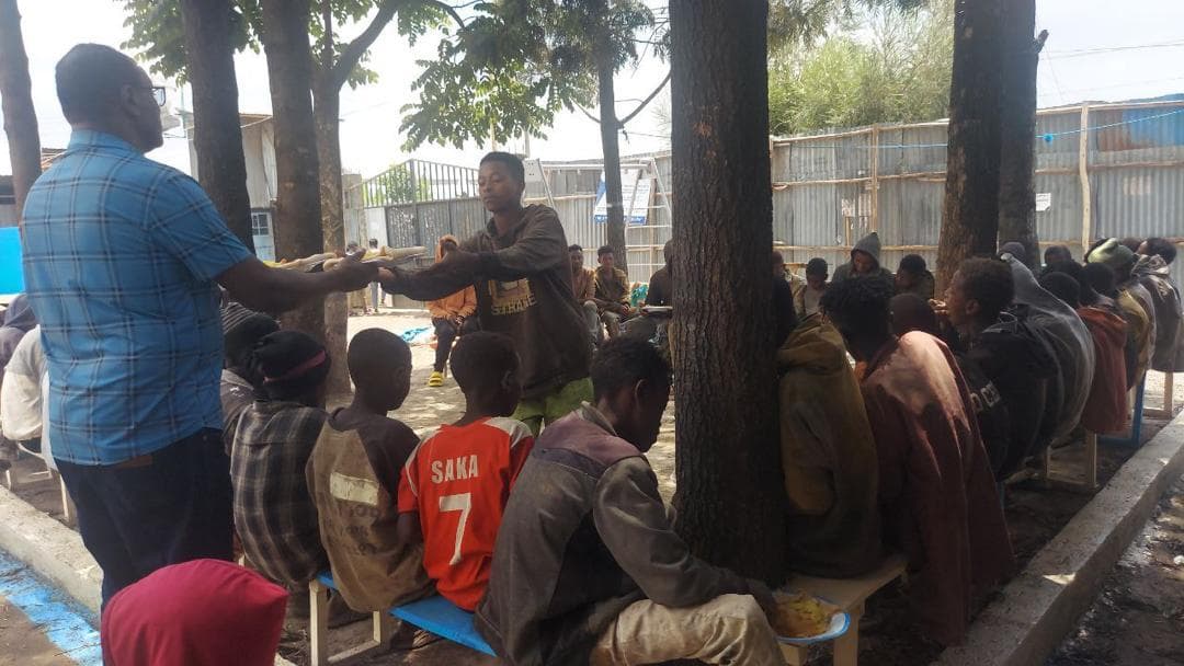 People sitting down to eat at the feeding programme